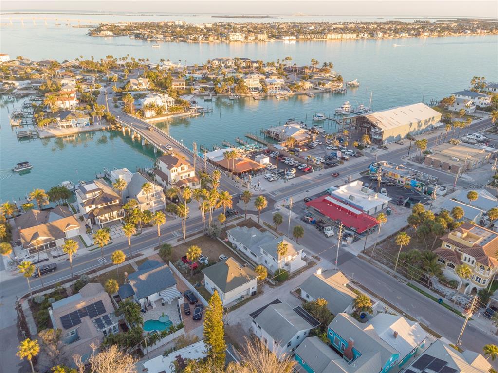 An aerial view shows a coastal town with a bridge, marina, and residential homes — 108 22ND AVENUE, ST PETE BEACH, FL