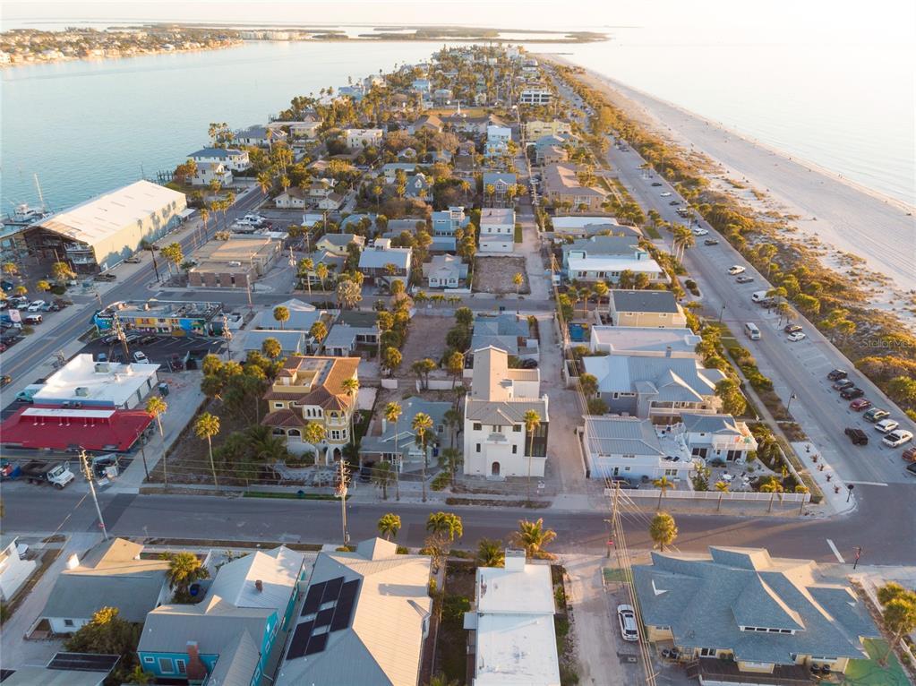 An aerial view shows a coastal neighborhood with houses, streets, and a beach — 108 22ND AVENUE, ST PETE BEACH, FL