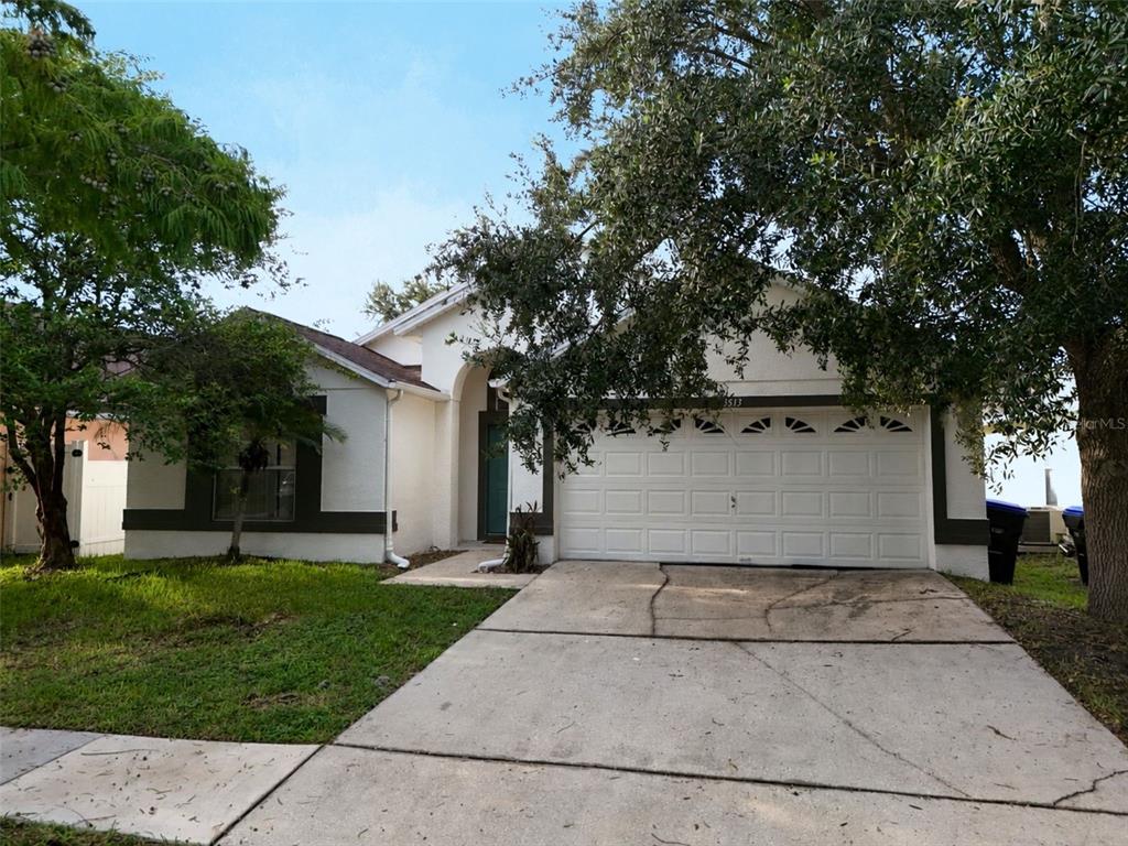 A single-story house with a two-car garage, a green front door, and large shade trees — 3513 MCALLISTER WAY, ORLANDO, FL