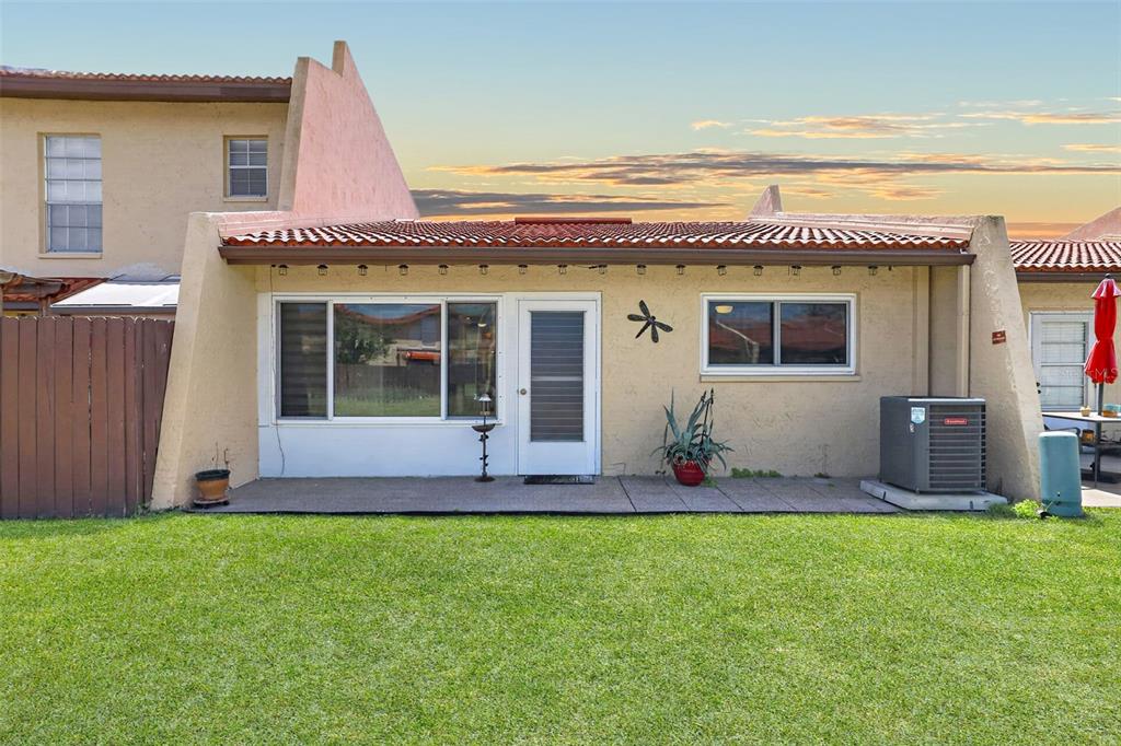 The exterior of a townhouse features a concrete patio, a grass lawn, and an AC unit — 7200 ULMERTON ROAD UNIT E3, LARGO, FL