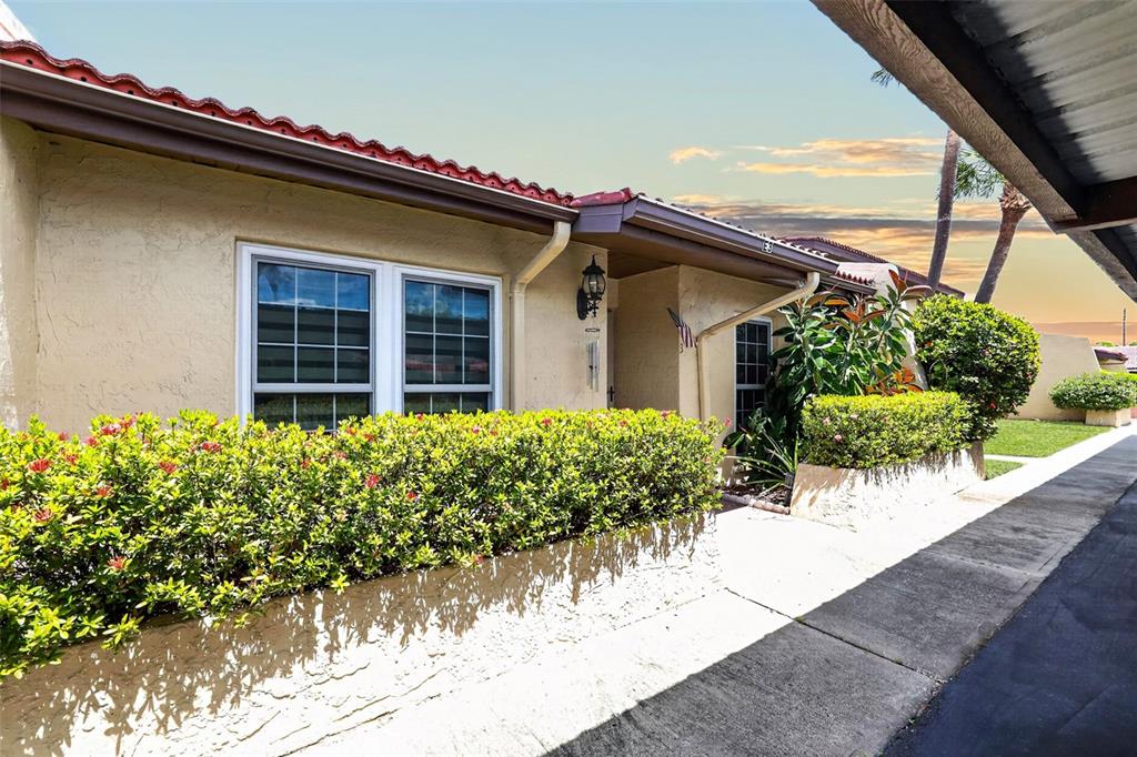 A beige stucco house exterior features a red tile roof and a landscaped hedge — 7200 ULMERTON ROAD UNIT E3, LARGO, FL