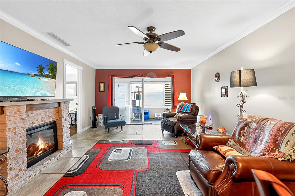 A living room features a stone fireplace, a large area rug, and sliding glass doors — 7200 ULMERTON ROAD UNIT E3, LARGO, FL