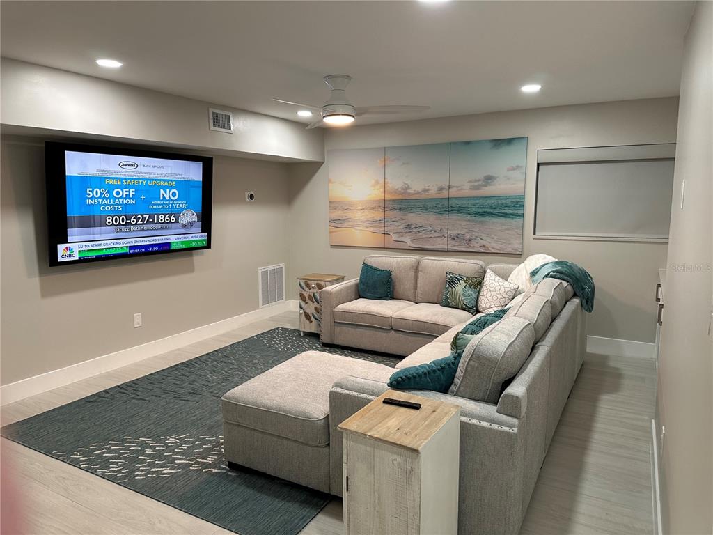 A living room features a large sectional sofa, a wall-mounted television, and beach-themed wall art — 745 ELDORADO AVENUE, CLEARWATER BEACH, FL