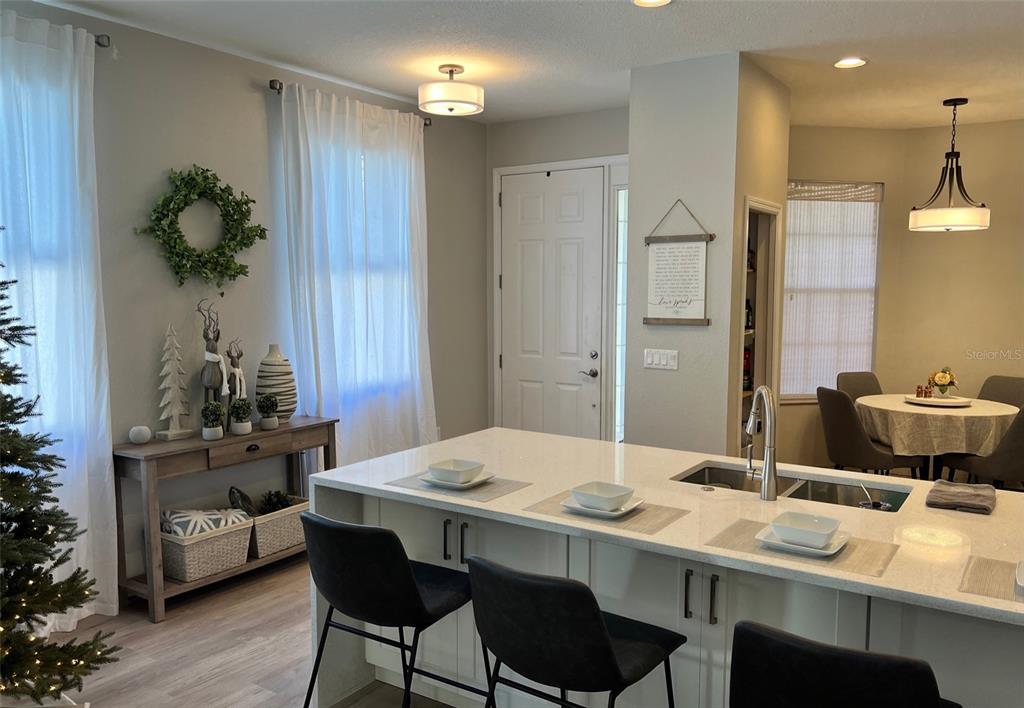 A kitchen features a white quartz island with bar seating, pendant lighting, and an adjacent dining area — 6138 KITERIDGE DRIVE, LITHIA, FL