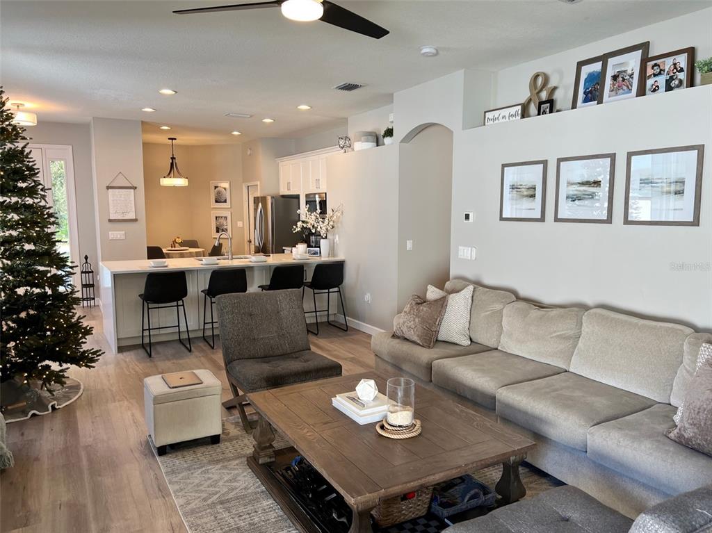 An open-concept living room and kitchen featuring a large sectional, coffee table, and breakfast bar — 6138 KITERIDGE DRIVE, LITHIA, FL