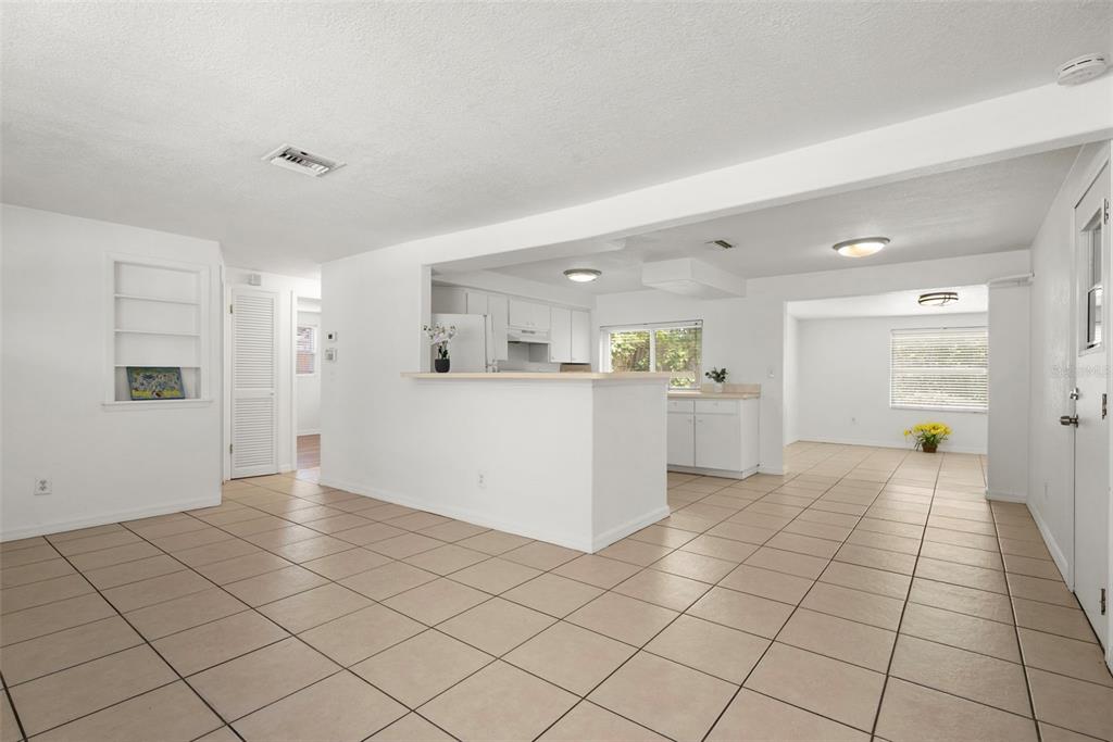 An open-concept living area with white walls, tile flooring, and a kitchen with a breakfast bar — 3438 KIMBERLY OAKS DRIVE, HOLIDAY, FL
