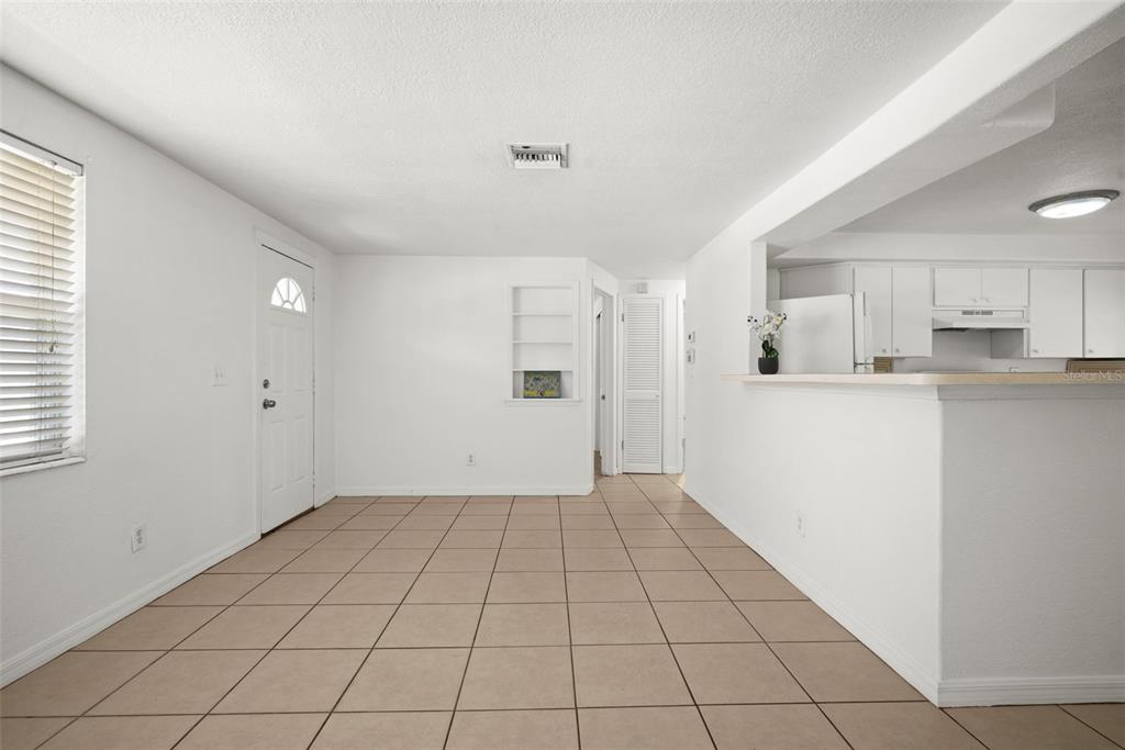 A dining area with white walls, tiled floors, a built-in shelf, and an adjacent kitchen — 3438 KIMBERLY OAKS DRIVE, HOLIDAY, FL