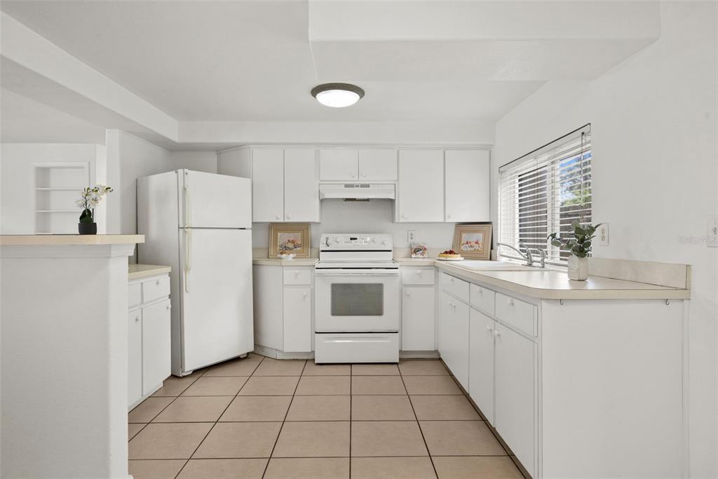 A white kitchen features tile flooring, white cabinetry, a white refrigerator, and a white stove — 3438 KIMBERLY OAKS DRIVE, HOLIDAY, FL
