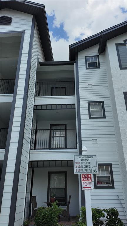 Exterior view of a three-story apartment building with balconies and a parking sign — 2209 ANTIGUA PLACE UNIT 826, KISSIMMEE, FL