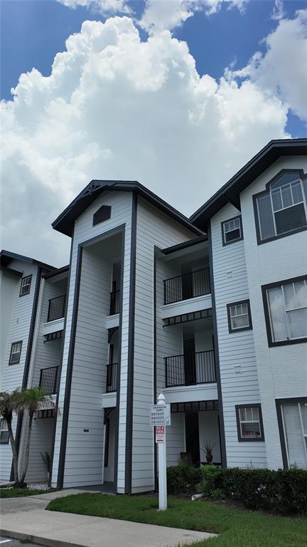 A multi-story apartment building with white horizontal siding, dark trim, and several balconies — 2209 ANTIGUA PLACE UNIT 826, KISSIMMEE, FL