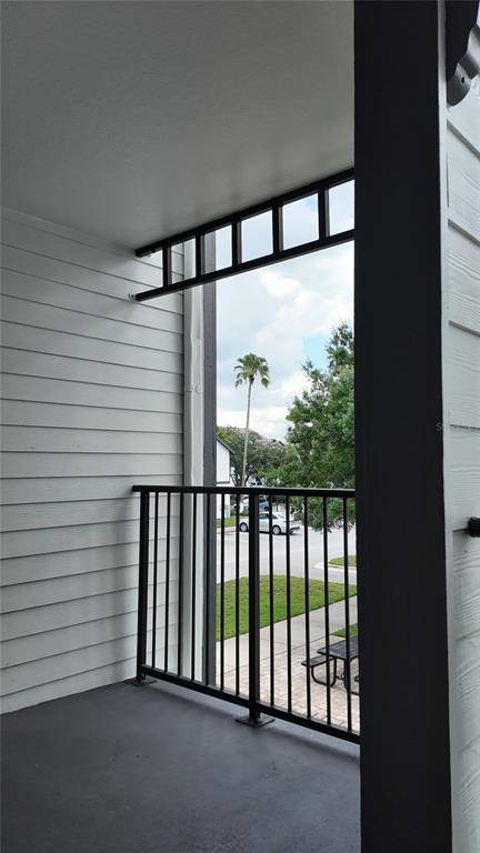 A covered balcony with a black metal railing overlooks a parking lot and palm tree — 2209 ANTIGUA PLACE UNIT 826, KISSIMMEE, FL