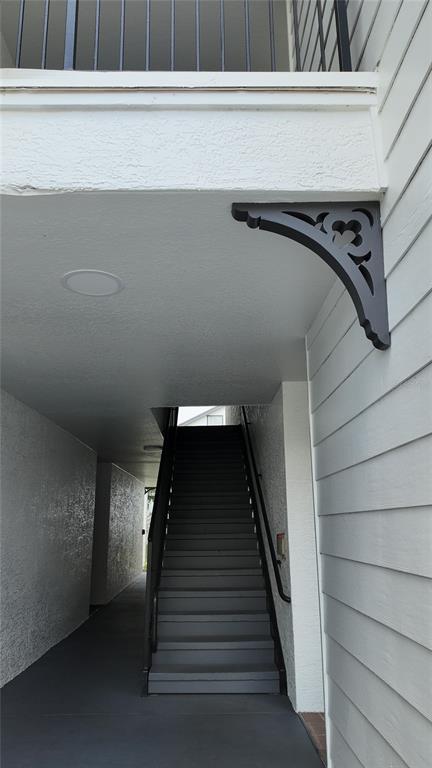 An outdoor staircase leads to an upper level balcony featuring a decorative dark wood bracket — 2209 ANTIGUA PLACE UNIT 826, KISSIMMEE, FL