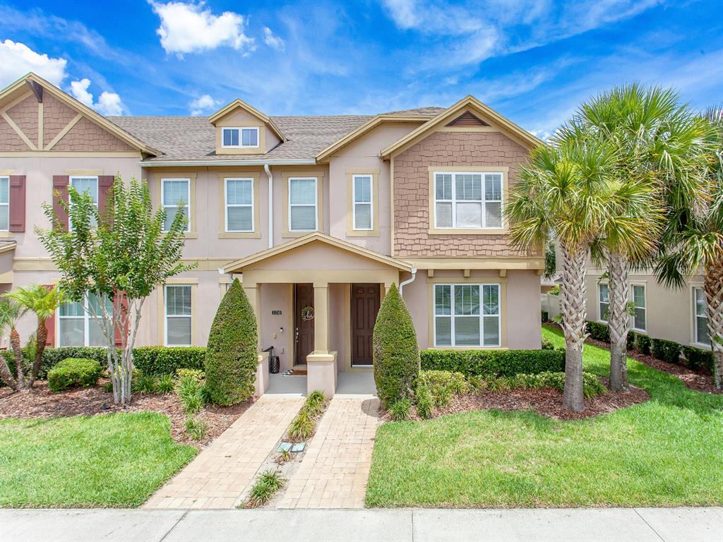 A two-story townhouse exterior features tan stucco, brown shingle siding, and a paved walkway — 11734 WATER RUN ALLEY, WINDERMERE, FL