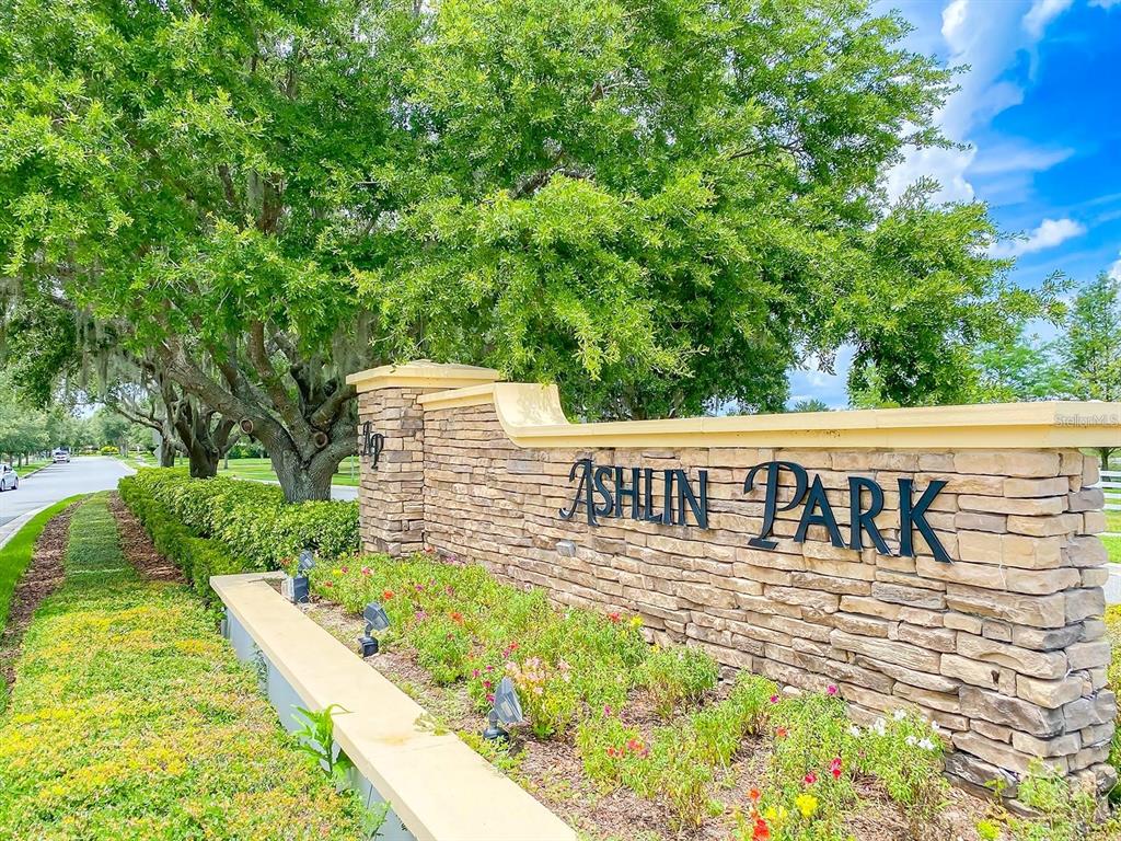A stone monument sign for Ashlin Park stands beside a road under large oak trees — 11734 WATER RUN ALLEY, WINDERMERE, FL