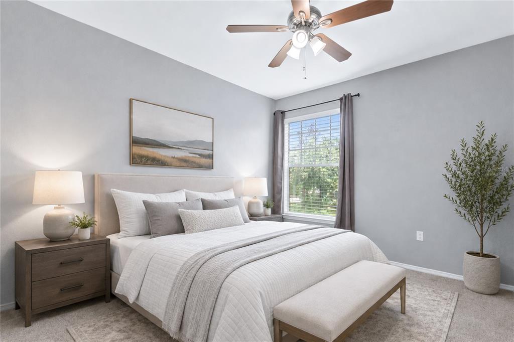 A bedroom features a bed with neutral bedding, two nightstands, a ceiling fan, and a window — 114 VISTA VERDI CIRCLE UNIT 216, LAKE MARY, FL