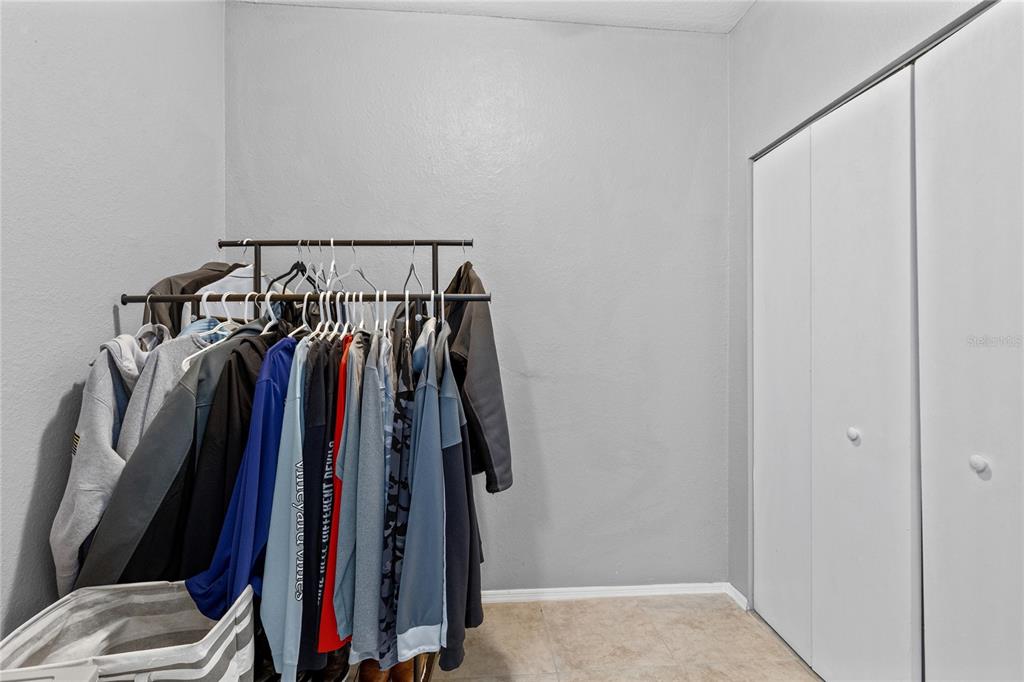 A room features a metal clothing rack filled with hanging garments beside a white closet — 114 VISTA VERDI CIRCLE UNIT 216, LAKE MARY, FL