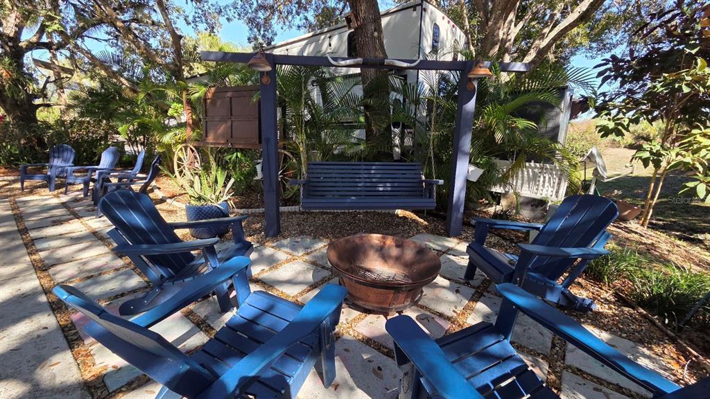 A backyard patio features a fire pit, a hanging bench, and several blue Adirondack chairs — 174 APPALOOSA TRAIL, RIVER RANCH, FL