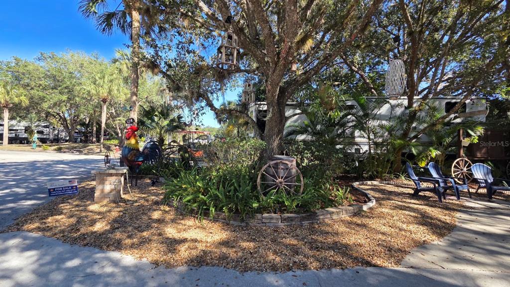 An outdoor area features a large tree, a decorative rooster statue, and a wooden wagon wheel — 174 APPALOOSA TRAIL, RIVER RANCH, FL