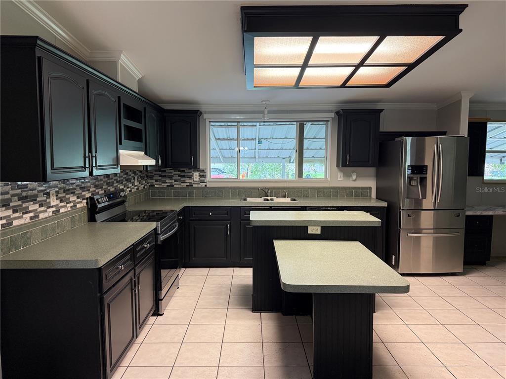A kitchen features black cabinets, green laminate countertops, stainless steel appliances, and a tiled floor — 3704 GARON AVENUE, RUSKIN, FL
