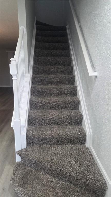 A carpeted staircase with a white wooden railing leads upward between two light-colored walls — 4439 SW 49TH AVENUE, OCALA, FL