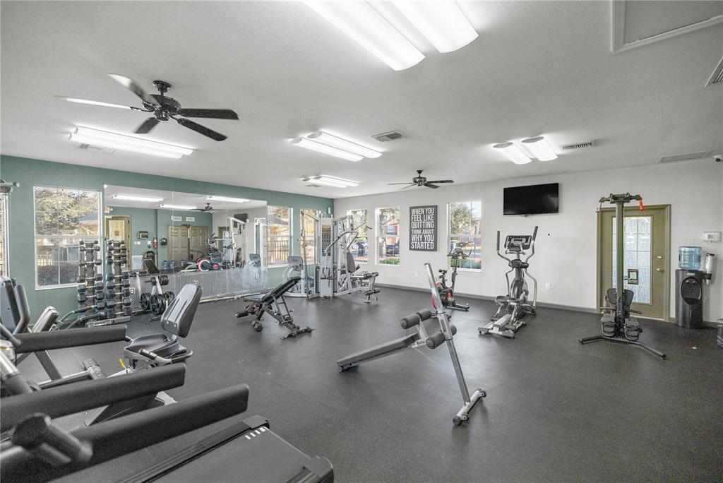 A fitness center with various exercise machines, rubber flooring, and a mirrored wall — 4439 SW 49TH AVENUE, OCALA, FL