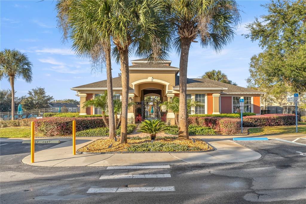 A tan community clubhouse building features a central arched entryway and two tall palm trees — 4439 SW 49TH AVENUE, OCALA, FL