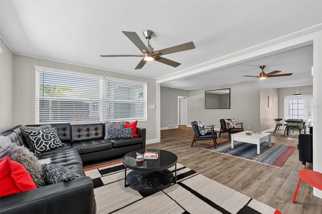 A living room features a black leather sectional, a round coffee table, and wood-look flooring — 2806 UPPER TANGELO DRIVE, SARASOTA, FL