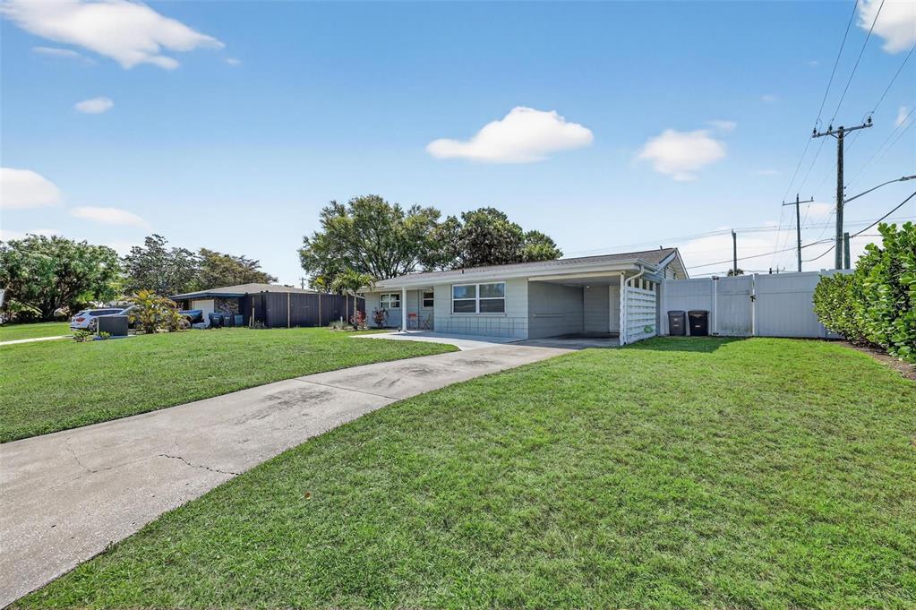 A single-story house with a concrete driveway, a carport, and a white privacy fence — 2806 UPPER TANGELO DRIVE, SARASOTA, FL