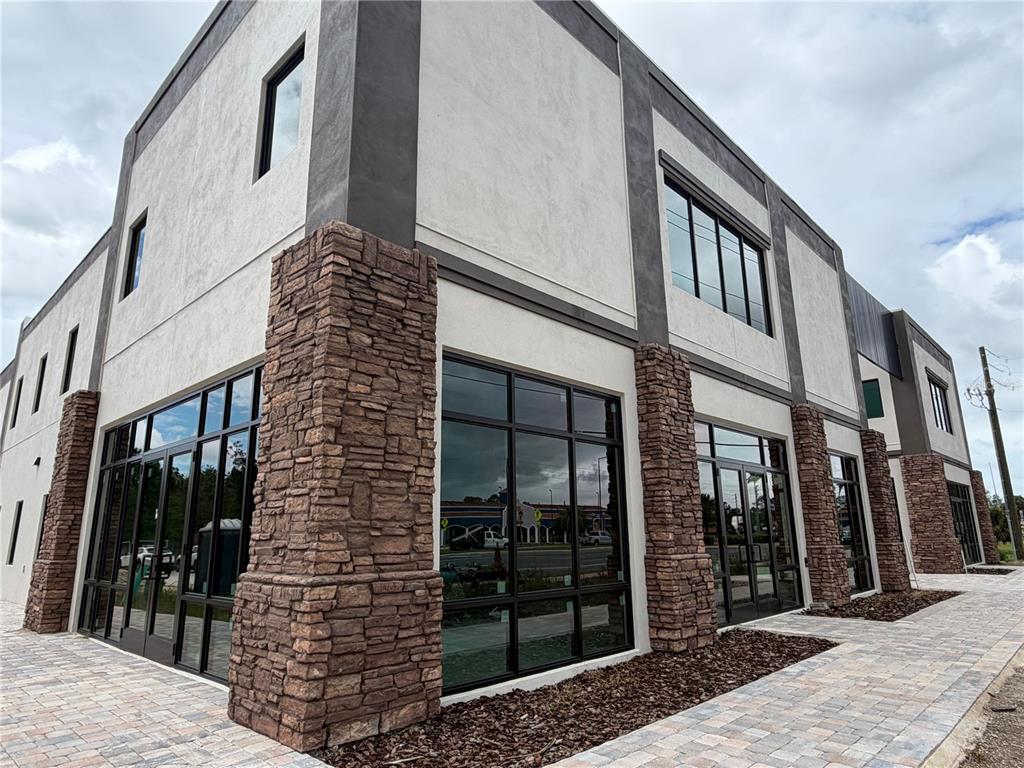 Exterior view of a modern commercial building with stone pillars and large glass windows — 4560 W IRLO BRONSON MEMORIAL HIGHWAY UNIT A, KISSIMMEE, FL