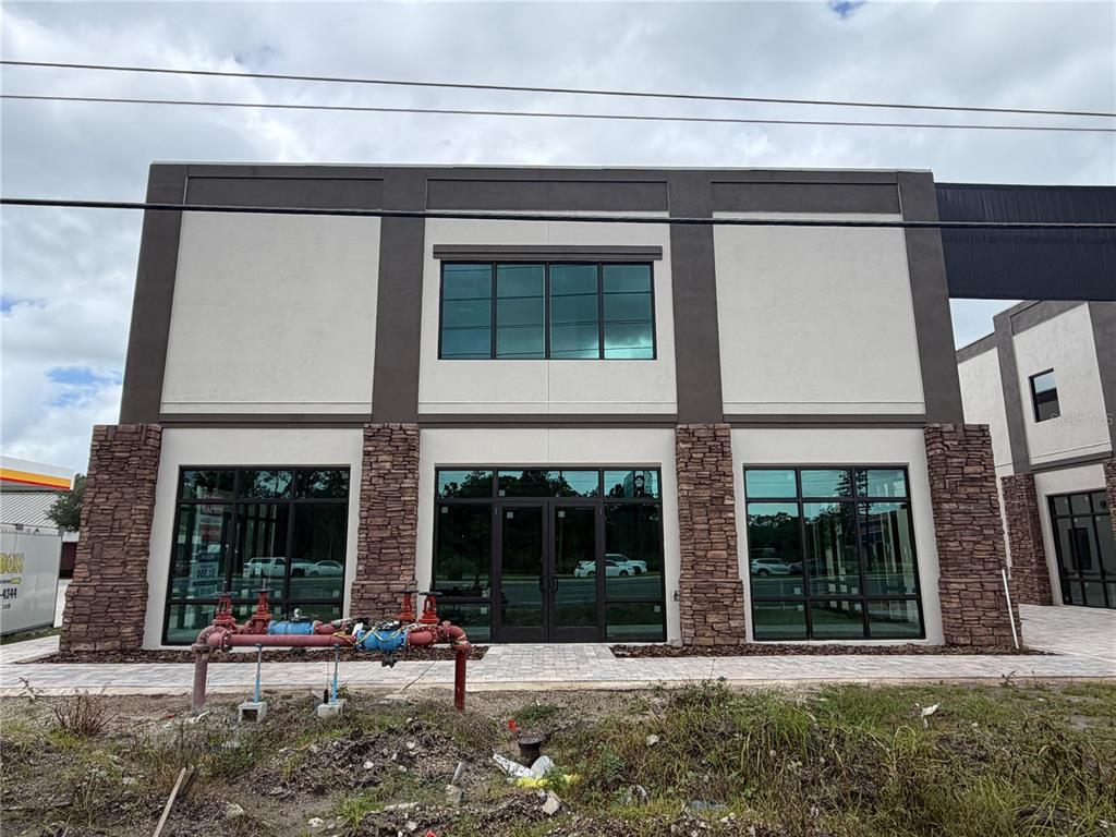 A two-story commercial building features stone accents, large glass windows, and a red fire hydrant — 4560 W IRLO BRONSON MEMORIAL HIGHWAY UNIT A, KISSIMMEE, FL