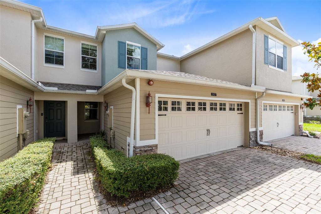 A two-story townhouse exterior features a paved driveway, a garage, and a small front walkway — 1327 PRIORY CIRCLE UNIT 1327, WINTER GARDEN, FL