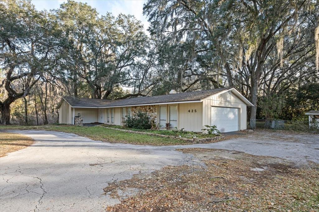 A single-story house with a stone facade, beige siding, and a two-car garage — 425 NW 79TH DRIVE, GAINESVILLE, FL