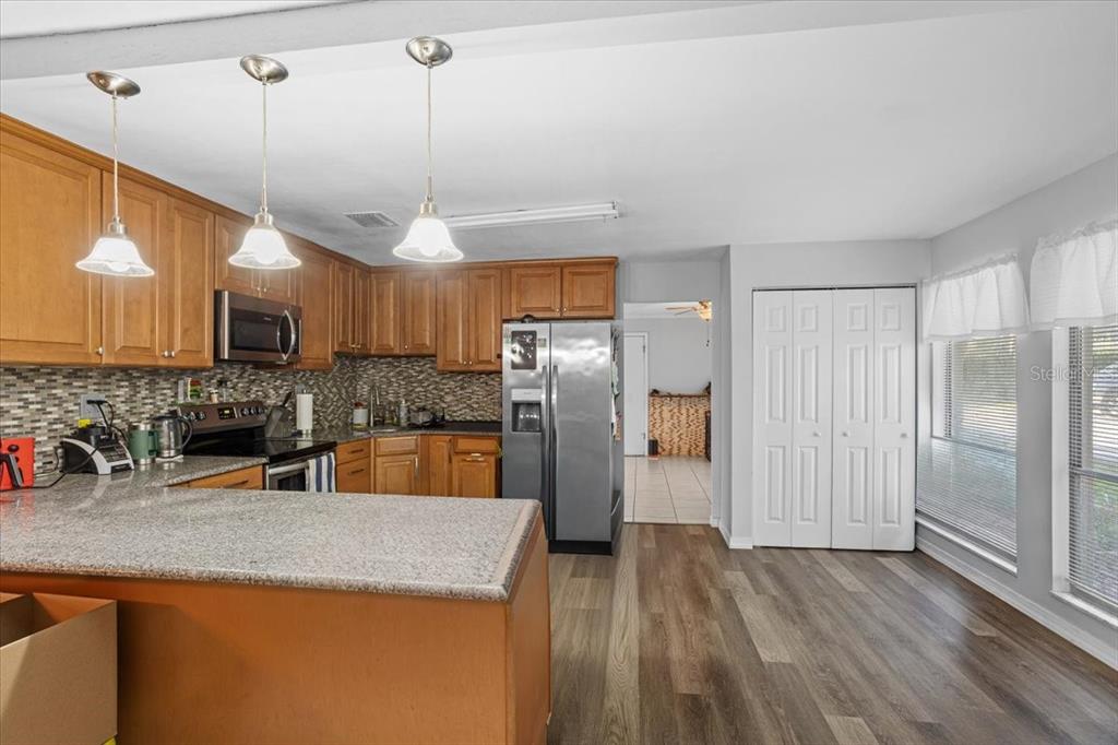 A kitchen with wood cabinets, stainless steel appliances, granite countertops, and wood-look flooring — 425 NW 79TH DRIVE, GAINESVILLE, FL