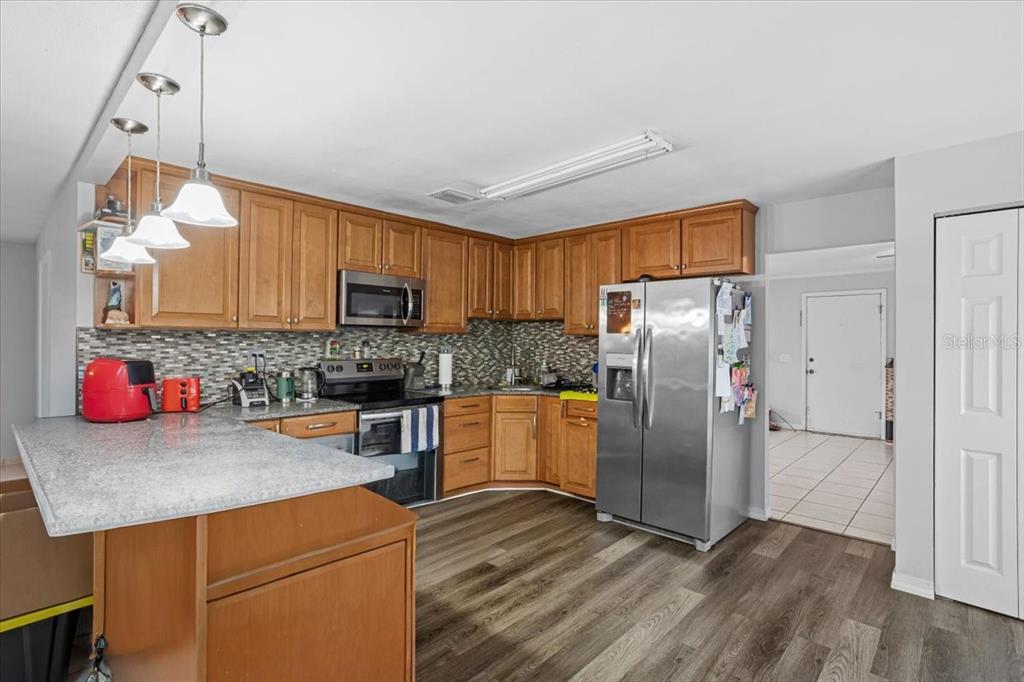 A kitchen features wood cabinets, stainless steel appliances, a tiled backsplash, and a breakfast bar — 425 NW 79TH DRIVE, GAINESVILLE, FL