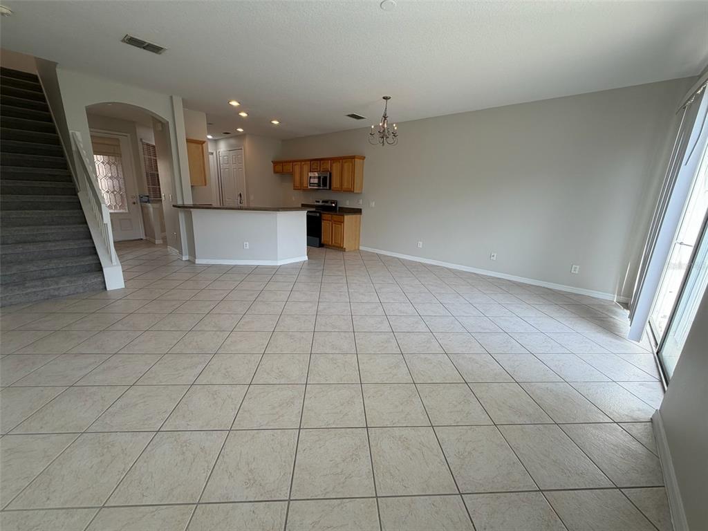 An open-concept living and kitchen area features tile flooring, light-colored walls, and a staircase — 7530 CRANES CREEK COURT, WINTER PARK, FL