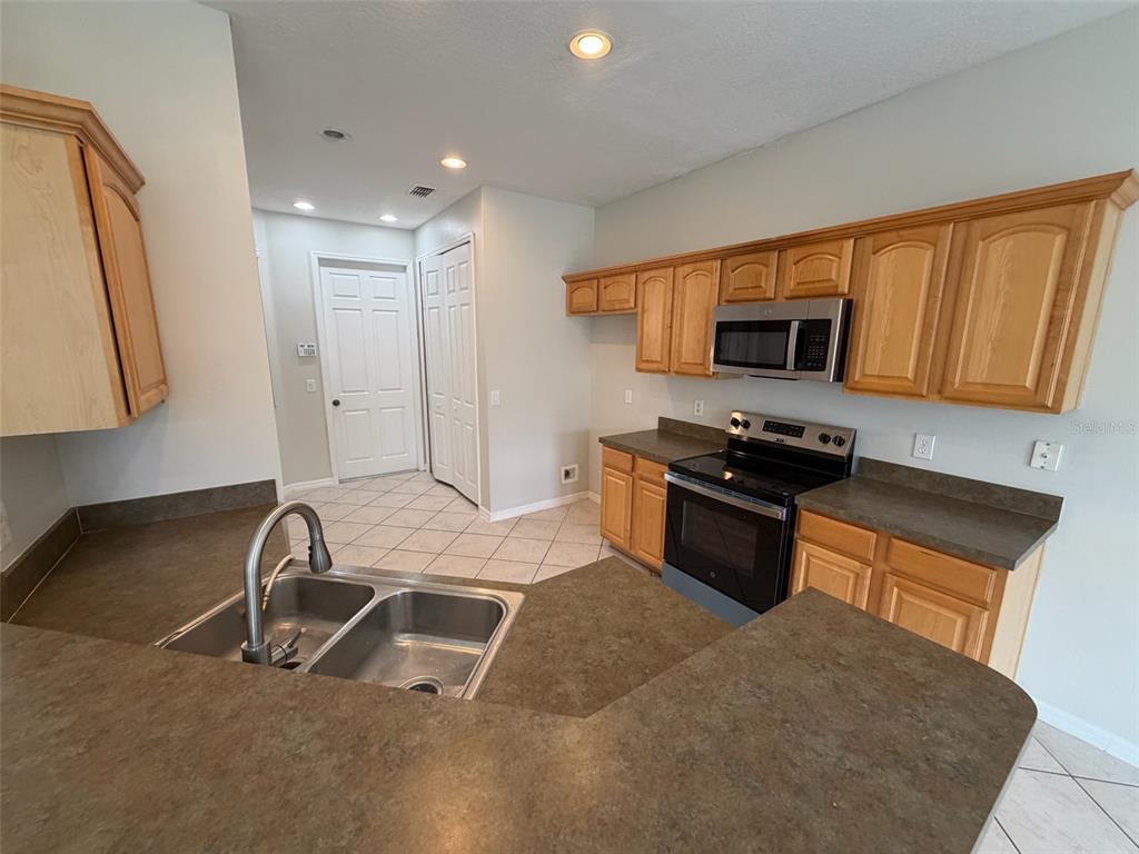 A kitchen features light wood cabinets, dark countertops, a double sink, and stainless steel appliances — 7530 CRANES CREEK COURT, WINTER PARK, FL