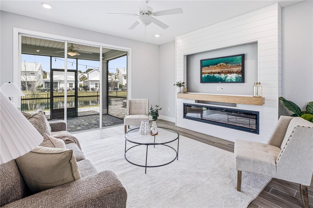 A living room features a shiplap fireplace wall, a television, and sliding doors to a patio — 126 OLD FORT TRAIL, ST JOHNS, FL
