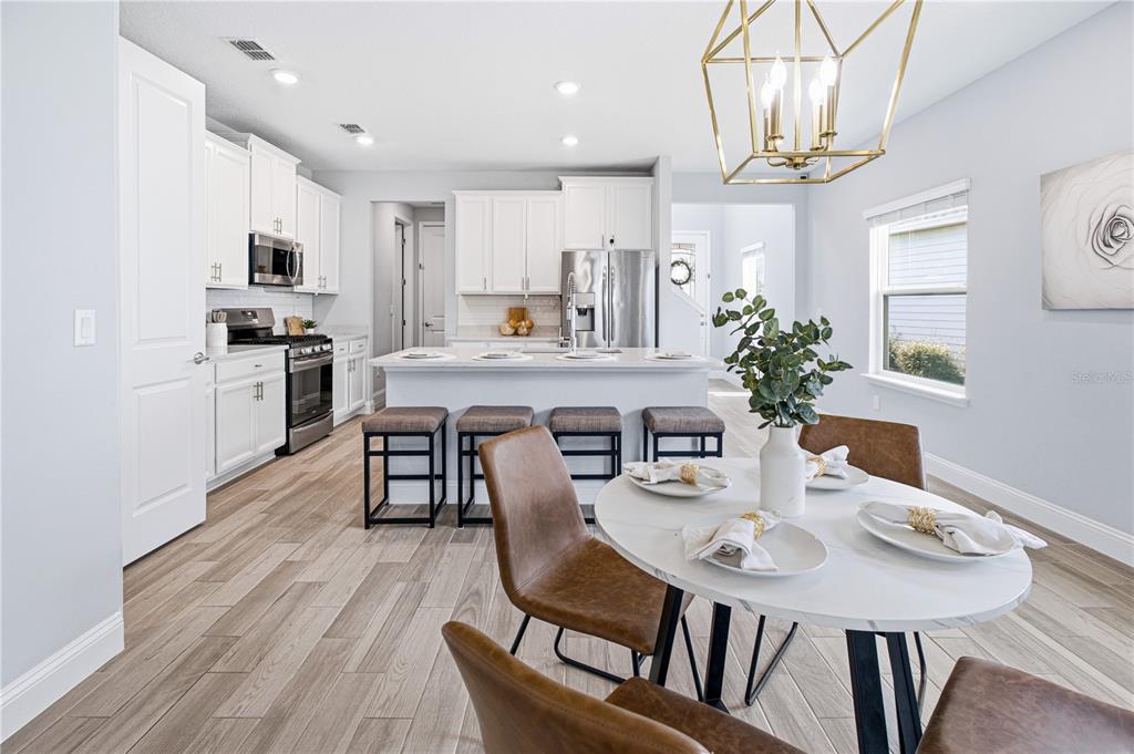 A bright kitchen features white cabinetry, a central island with bar stools, and a dining area — 126 OLD FORT TRAIL, ST JOHNS, FL