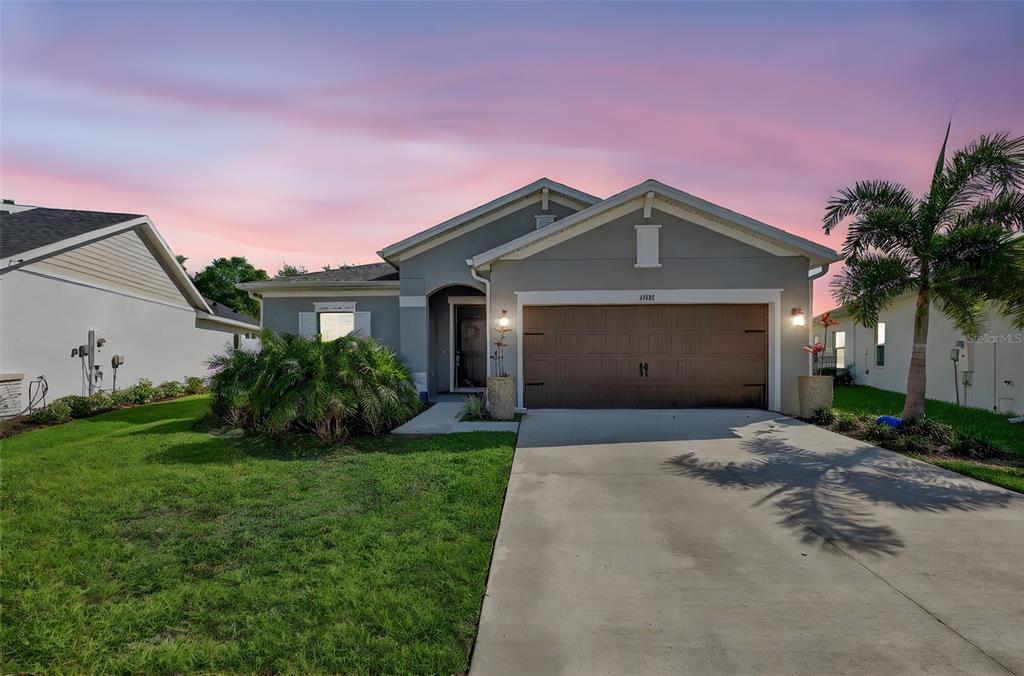 A gray single-story house with a brown garage door and a palm tree in front — 11912 RICHMOND TRAIL, PARRISH, FL