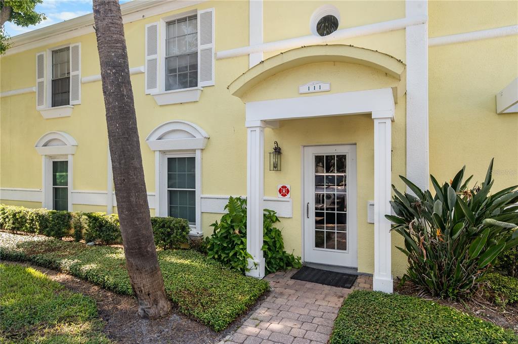 A yellow two-story building exterior features a white covered entryway with a glass-paneled door — 111 SEAHORSE DRIVE SE UNIT A, ST PETERSBURG, FL