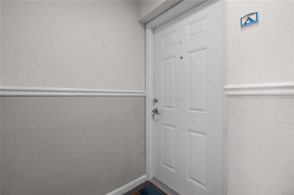 A white front door with a letter A sign is set against light gray walls — 111 SEAHORSE DRIVE SE UNIT A, ST PETERSBURG, FL
