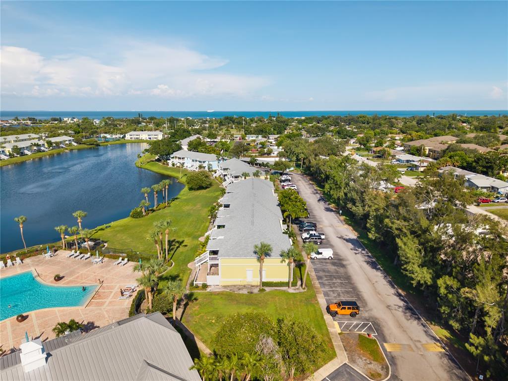 An aerial view shows a yellow apartment building next to a pool and a lake — 111 SEAHORSE DRIVE SE UNIT A, ST PETERSBURG, FL