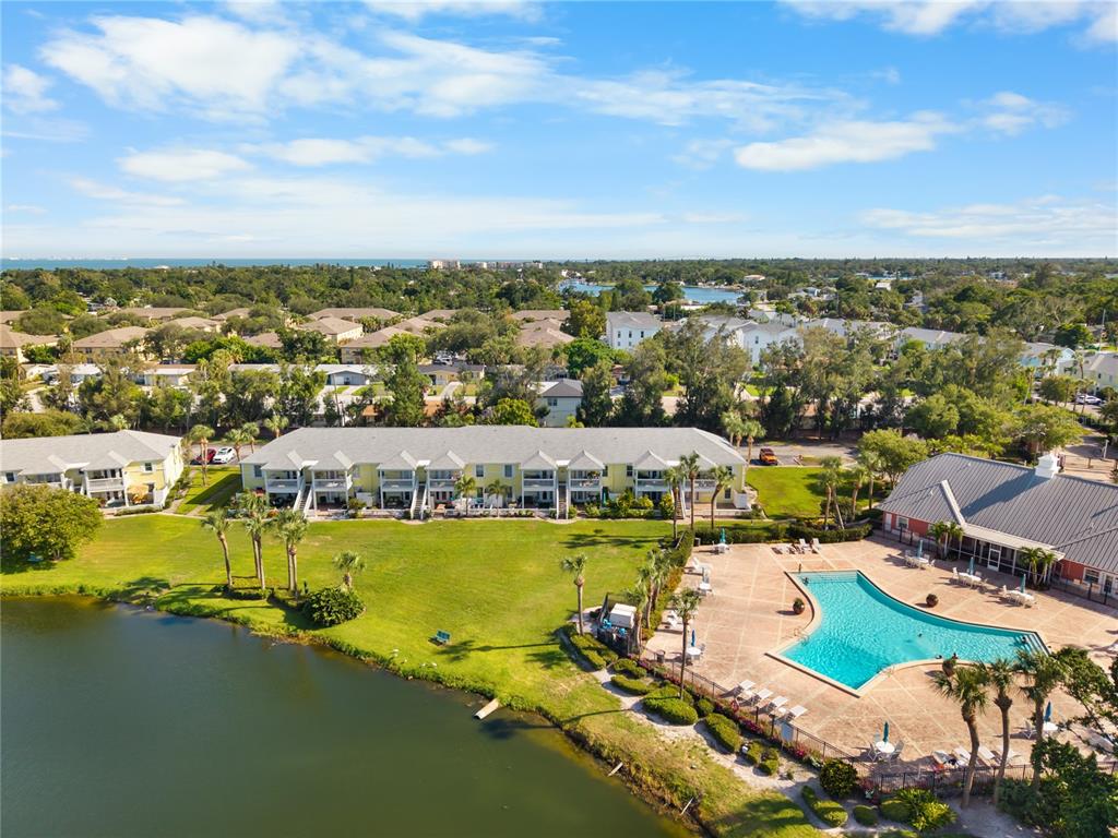 An aerial view shows a multi-story apartment building, a swimming pool, and a lake — 111 SEAHORSE DRIVE SE UNIT A, ST PETERSBURG, FL