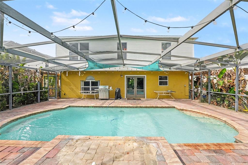 A backyard swimming pool with a brick deck is enclosed by a screened-in lanai structure — 5888 WINDRIDGE DRIVE, WINTER HAVEN, FL