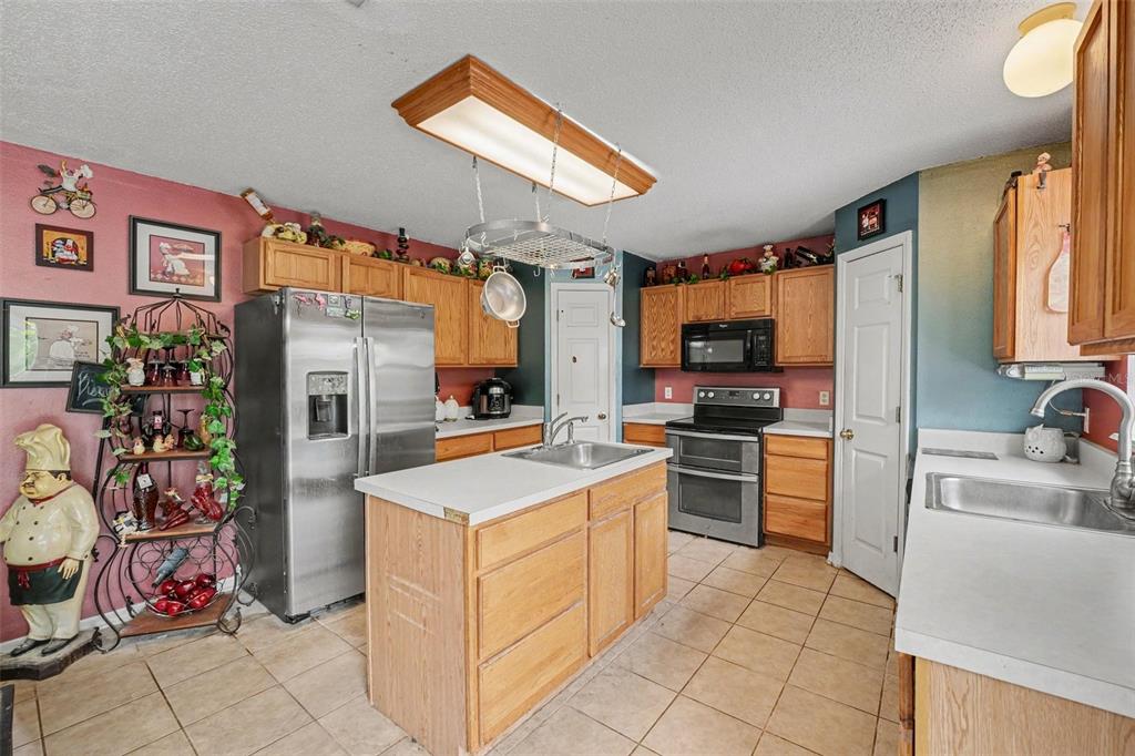 A kitchen with wooden cabinets, stainless steel appliances, a center island, and tiled flooring — 5888 WINDRIDGE DRIVE, WINTER HAVEN, FL
