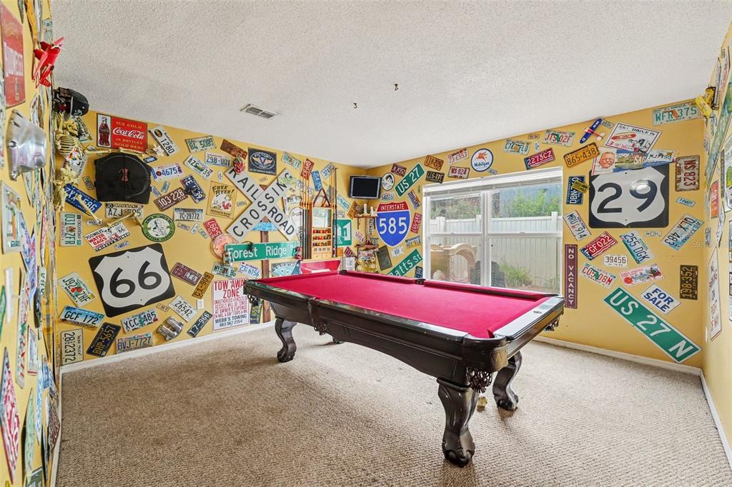 A game room features a red pool table and walls covered in vintage license plates — 5888 WINDRIDGE DRIVE, WINTER HAVEN, FL