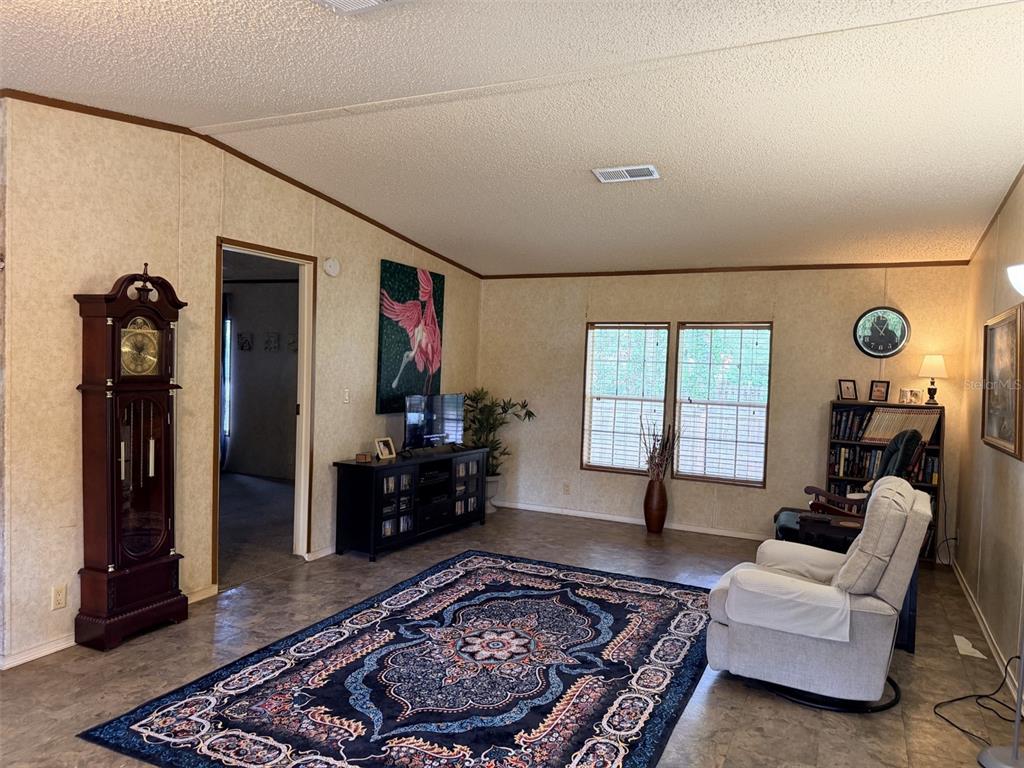 A living room features a grandfather clock, a large area rug, and a television console — 230 E RODGERS BOULEVARD, CHIEFLAND, FL
