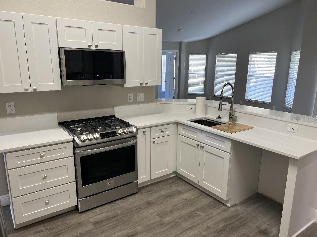 A kitchen features white cabinets, stainless steel appliances, and a peninsula with a sink — 735 HURLEY DRIVE, WINTER GARDEN, FL