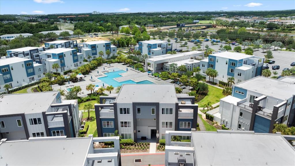 An aerial view shows a modern apartment complex with a central swimming pool and parking — 7740 SANDY RIDGE DRIVE UNIT 112, REUNION, FL