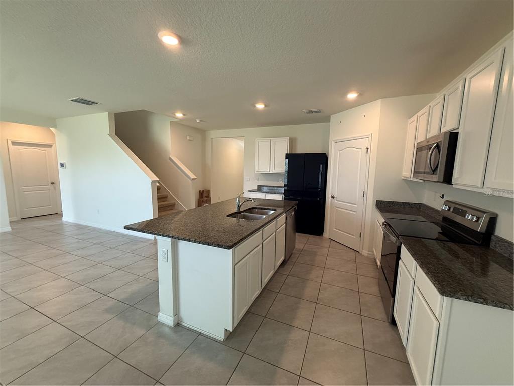 A kitchen with white cabinets, granite countertops, a central island, and tile flooring — 11106 AMBER RIDGE DRIVE, ZELLWOOD, FL
